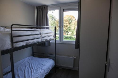 um quarto com 2 beliches e uma janela em Groeps Villa 24 pers. em Voorthuizen