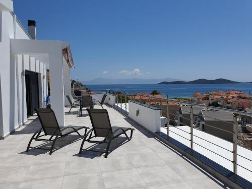 una fila de sillas en un balcón con vistas al océano en Aelia Apartments, en Nea Peramos