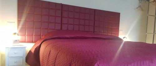 una camera con un letto rosa con una grande testiera del letto di Casa Il Germoglio a Montecatini Terme