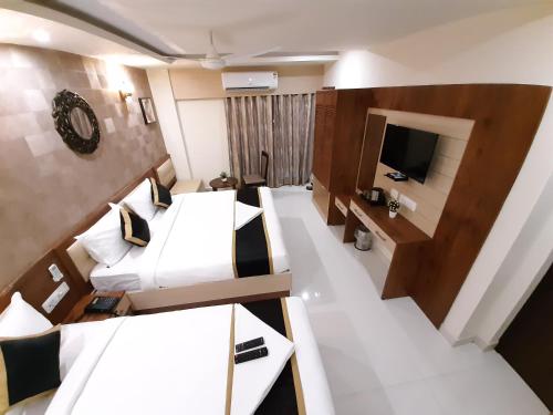 a hotel room with two beds and a tv at Liza Regency in Chennai