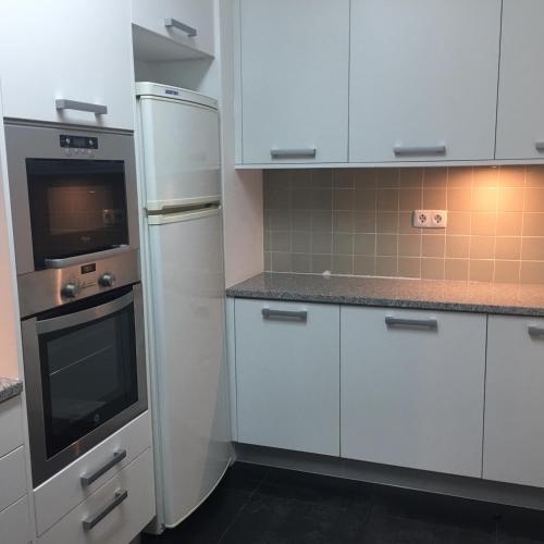 a kitchen with white cabinets and a stove and refrigerator at Azores Avenida E Apartment T3 in Ponta Delgada
