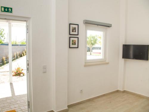 Dieses weiße Zimmer verfügt über ein Fenster und einen TV an der Wand. in der Unterkunft Casa das Pipas #4 in Pinhal Novo
