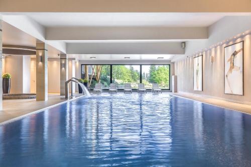 a swimming pool in a hotel room with chairs and a swimming poolvisorvisorvisor at Kocierz Resort in Targanice