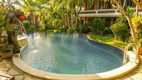 a swimming pool with a fountain in a garden at Hotel Suma in Lovina