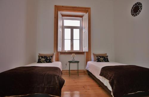 two beds in a room with a window at Casa Joana B&B in Cascais