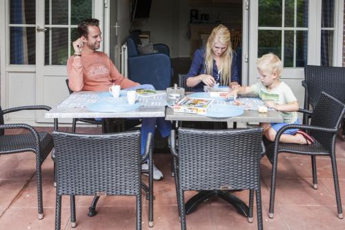 a man and a woman sitting at a table with a child at Zeumeren 6 pers. bungalow in Voorthuizen
