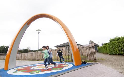 a group of children walking through an arch in a playground at Zeumeren 6 pers. bungalow in Voorthuizen