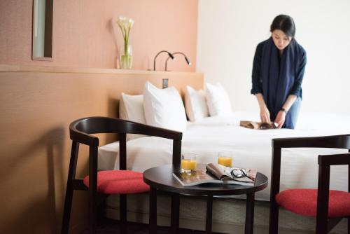the b kobe في كوبه: امرأة تقف على سرير في غرفة الفندق