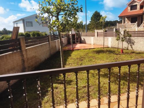 une clôture devant une maison avec un arbre dans l'établissement Apartamento Mirador de Corrubedo, à Corrubedo