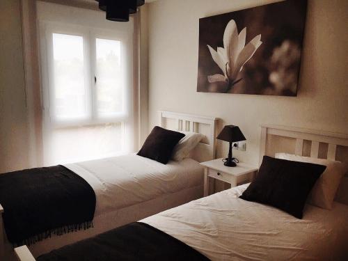 2 Betten in einem Schlafzimmer mit Fenster in der Unterkunft Apartamento Mirador de Corrubedo in Corrubedo