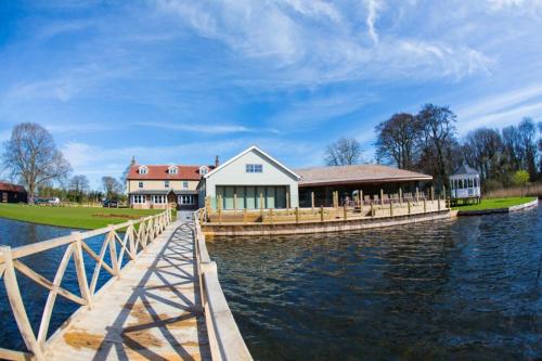a house on the water next to a dock at The Boathouse in Rollesby