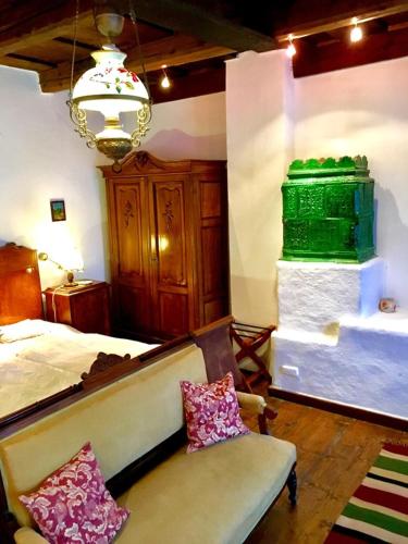 a bedroom with a bed and a couch and a chandelier at Count Kálnoky's Transylvanian Guesthouses in Micloşoara
