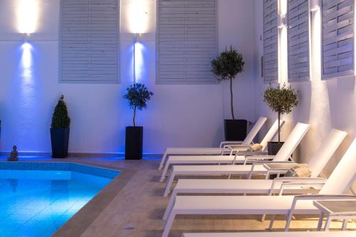 a pool with white chairs and a swimming pool at Naiades Marina Hotel in Agios Nikolaos