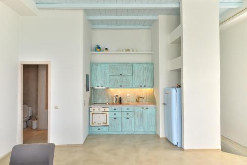 a kitchen with blue cabinets and a refrigerator at White Memories, seafront luxury apartment Mykonos in Mýkonos City
