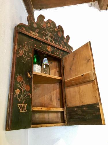 an old wooden cabinet with two bottles in it at Count Kálnoky's Transylvanian Guesthouses in Micloşoara