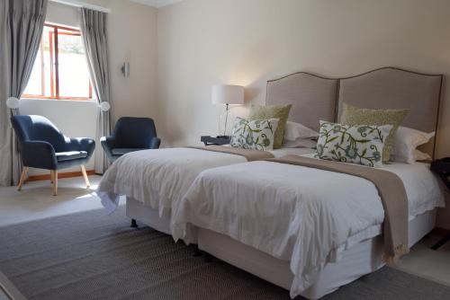 a white bedroom with a large bed and a chair at Cultivar Boutique Hotel in Stellenbosch