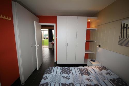 una camera con letto e parete rossa di Appartement Acacia/Orchidee 2-4p a De Haan