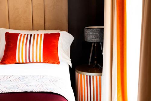 a bed with a colorful pillow and a lamp at Amadomus Luxury Suites in Naples