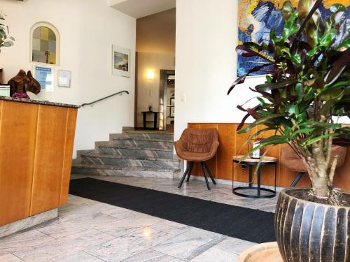 a waiting room with a potted plant and stairs at Hotel Wegener in Mannheim