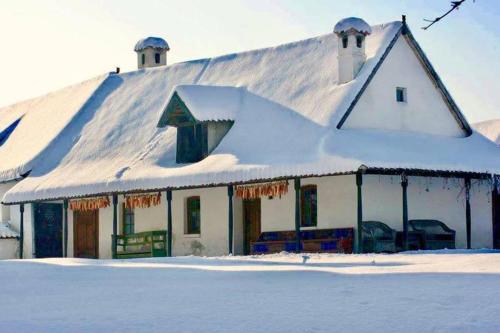 a white house with snow on top of it at Count Kálnoky's Transylvanian Guesthouses in Micloşoara