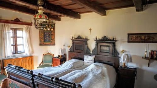 a bedroom with a large bed and a cross on the wall at Count Kálnoky's Transylvanian Guesthouses in Micloşoara