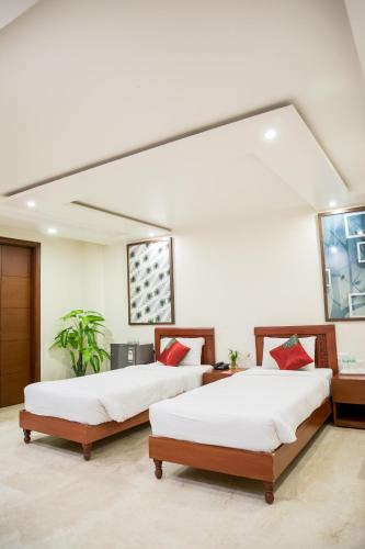two beds in a room with white walls at SM Palace (Near Apollo Hospital) in New Delhi