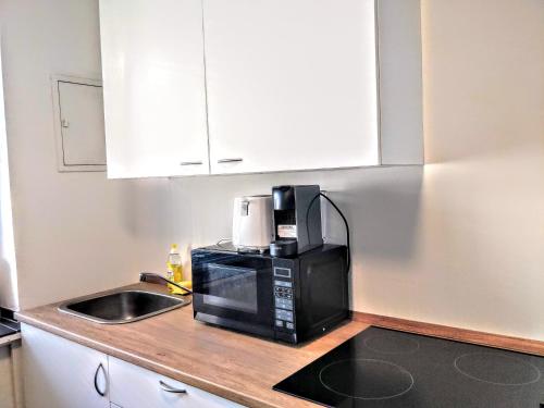 a kitchen with a microwave and a sink at AVI City Apartments MainHouse in Düsseldorf