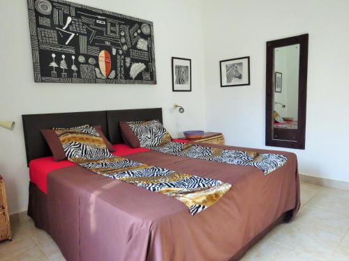 een groot bed in een kamer met een spiegel bij Kingfishers Apartments in Bijilo