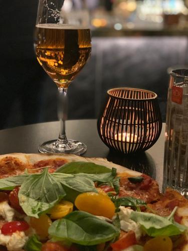 a pizza on a table with a glass of wine at Best Western Malmo Arena Hotel in Malmö