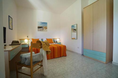 ein Schlafzimmer mit einem Bett und einem Schreibtisch mit einem Hut auf einem Stuhl in der Unterkunft Apulia Hotel Sellia Marina in Sellia Marina