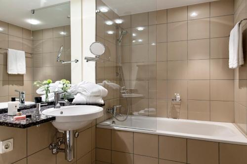 een badkamer met een wastafel, een douche en een bad bij Hotel Kleines Meer in Waren