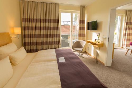 a hotel room with a large bed and a desk at Hotel Kleines Meer in Waren