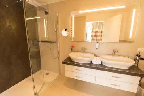 a bathroom with two sinks and a shower at Hotel Kleines Meer in Waren