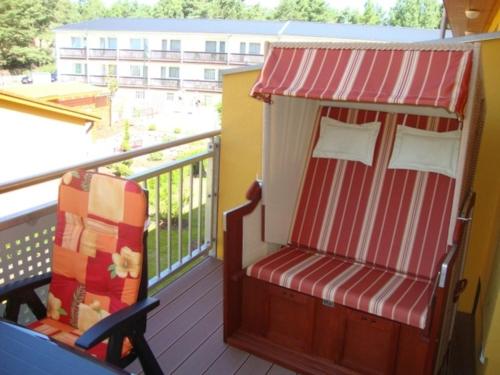 a porch with a red and white chair on a balcony at Zempin Ostseepark WE 36 _Insel Use in Zempin