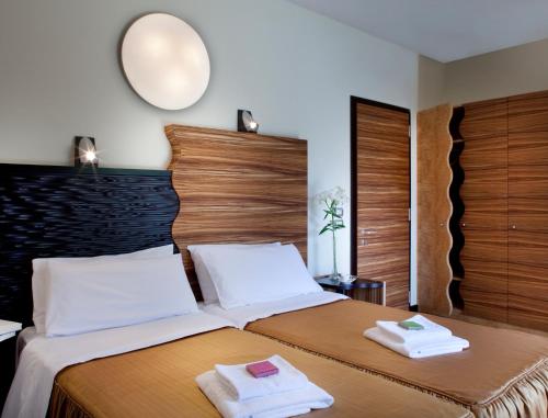 a bedroom with two beds and a mirror on the wall at Hotel Villa Giulia in Gargnano