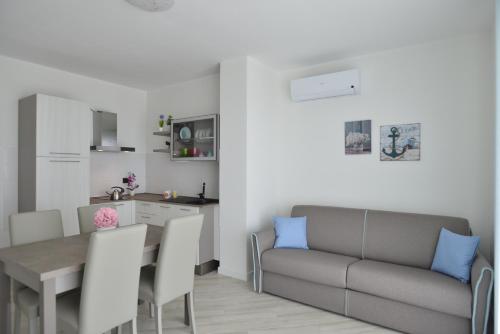 a kitchen and a living room with a table and a couch at Milena Suite Apartments in Alghero