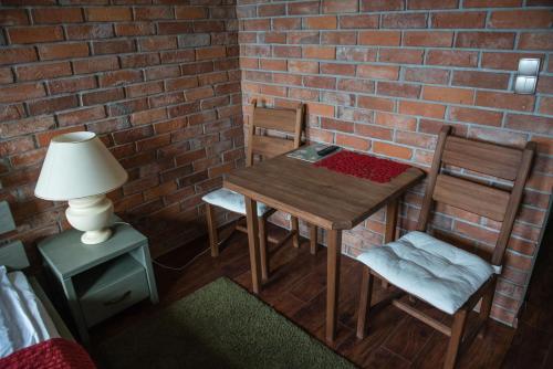 a table with two chairs and a lamp next to a brick wall at Apartamenty Faust in Ełk