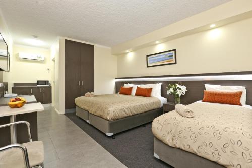 a hotel room with two beds and a desk at Morphettville Motor Inn in Glenelg