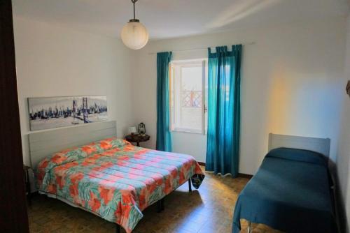 a bedroom with a bed and a window with blue curtains at Bilocale Pascoli in Santa Teresa Gallura