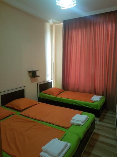 two beds in a room with red curtains at Apartment Nodmax in Ureki