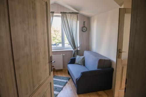 a living room with a blue chair and a window at Apartamenty Faust in Ełk