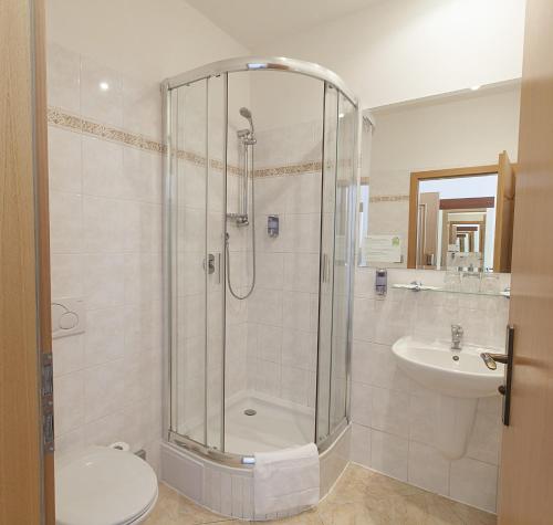a bathroom with a shower and a toilet and a sink at Hotel Atos in Prague