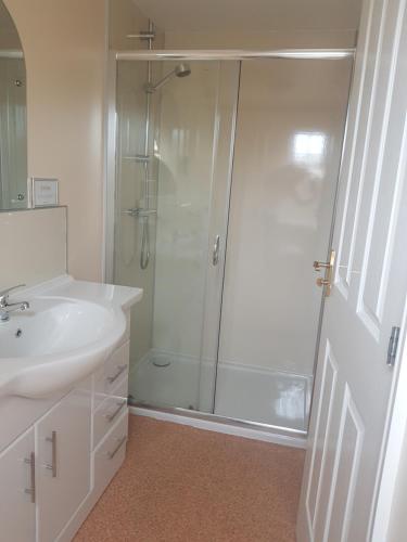 ein weißes Bad mit einer Dusche und einem Waschbecken in der Unterkunft The Station Hotel in Alness
