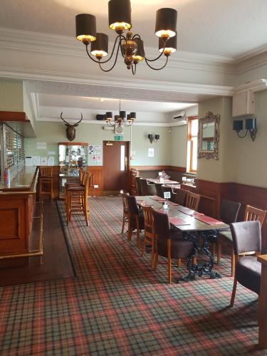 un restaurant avec des tables et des chaises ainsi qu'une salle à manger dans l'établissement The Station Hotel, à Alness