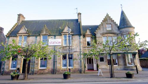 a large brick building with a clock on the front of it at The Station Hotel in Alness