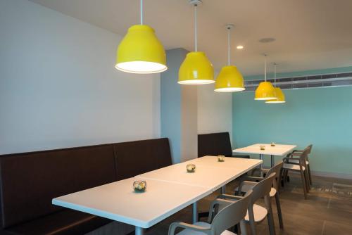 a dining room with two tables and yellow pendant lights at Calypso Beach Hotel in San Andrés