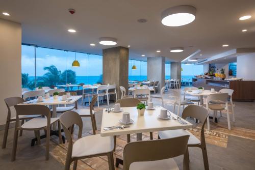 a restaurant with tables and chairs with the ocean in the background at Calypso Beach Hotel in San Andrés