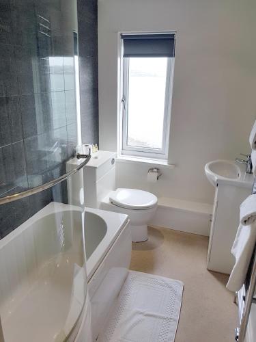 a white bathroom with a toilet and a sink at Ferry House Inn in Milford Haven