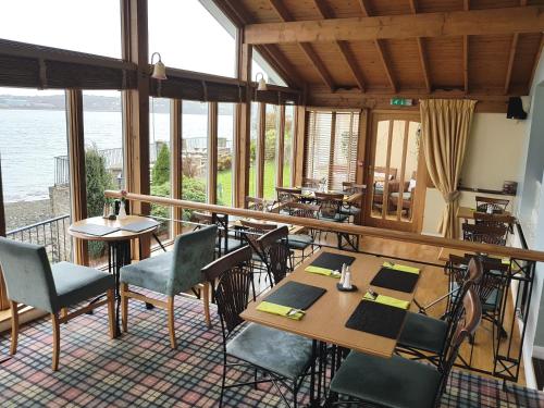 a restaurant with tables and chairs in a room with windows at Ferry House Inn in Milford Haven