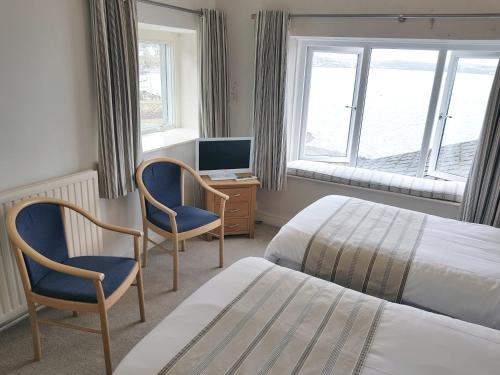 a bedroom with two beds and a desk with a television at Ferry House Inn in Milford Haven